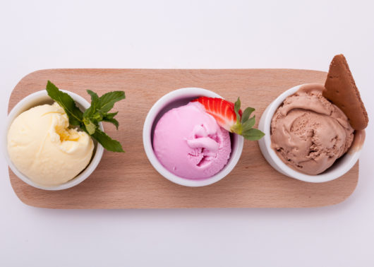 Three scoops of ice cream on a wooden board