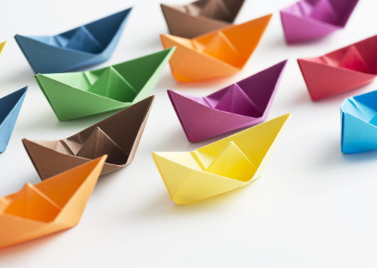 Multicolored paper boats representing new staff